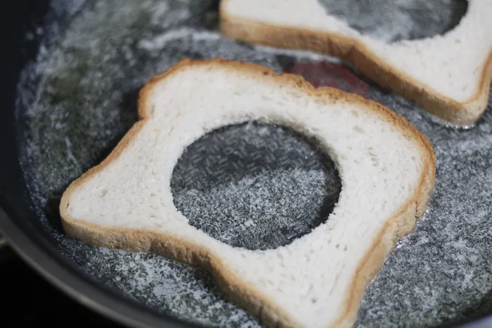 adding bread to the skillet for egg in the hole