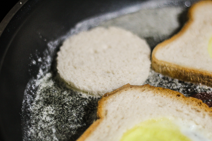 adding bread rounds to the pan with egg in the hole