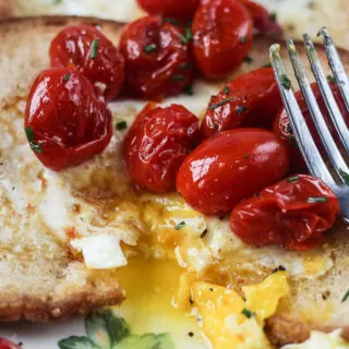 egg in the hole with cut opening and bursted tomatoes