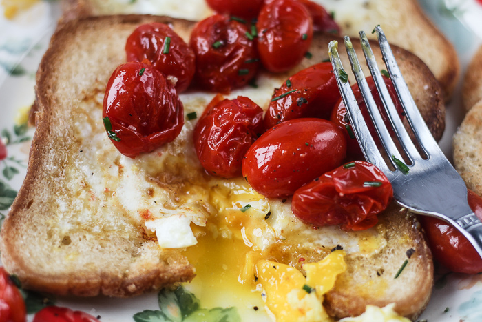 egg in the hole with cut opening and bursted tomatoes