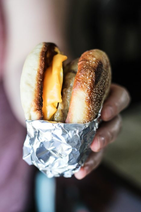 holding breakfast sandwich wrapped in aluminum foil