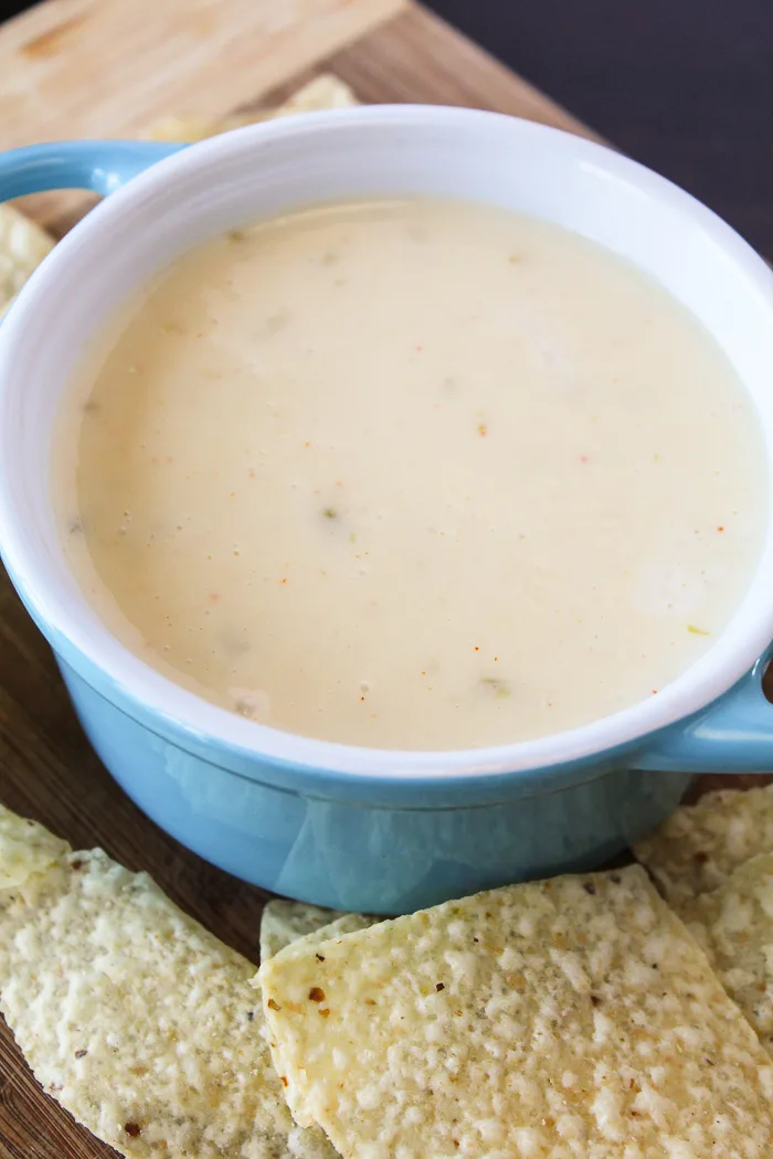 long shot of cheese dip in blue bowl with tortilla chips