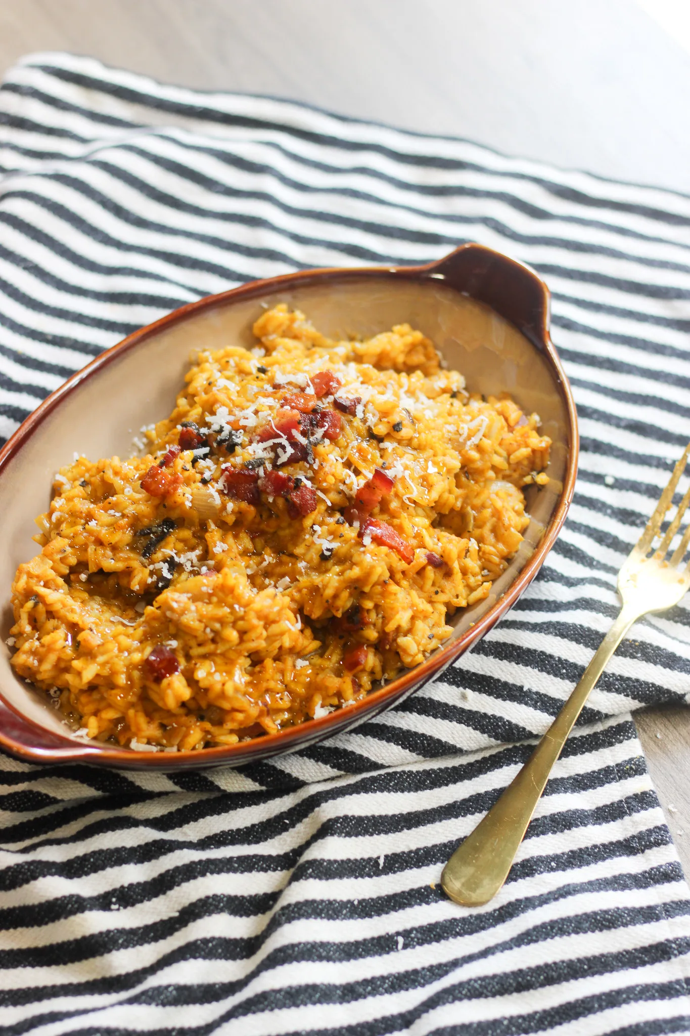 Plated pumpkin risotto served with extra Parmesan and bacon garnish