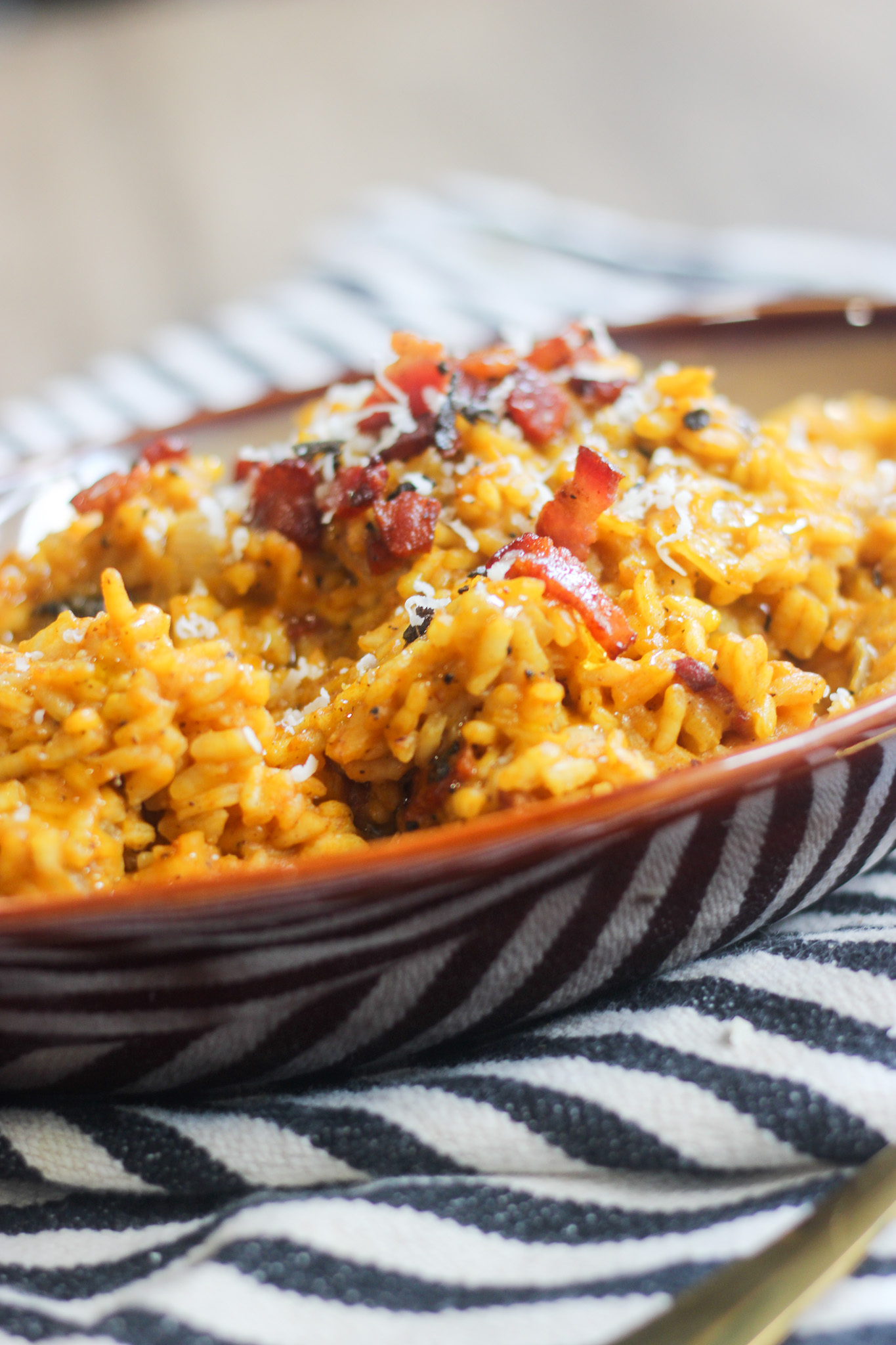 Close-up bowl of creamy pumpkin risotto topped with Parmesan and fresh herbs